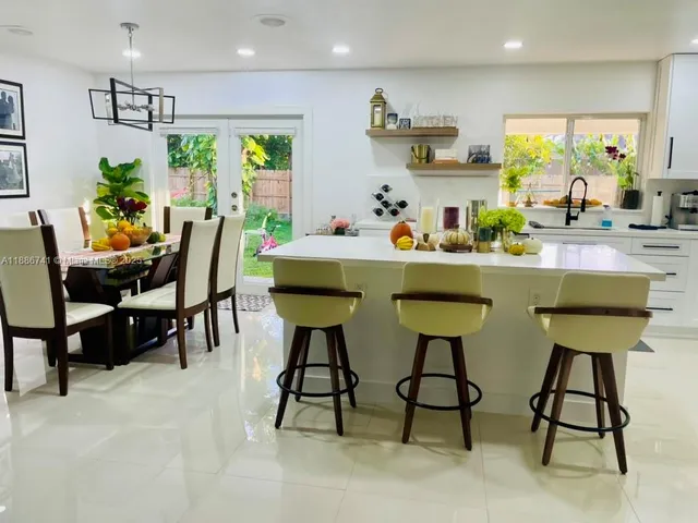 a kitchen with stainless steel appliances a white table chairs and a refrigerator