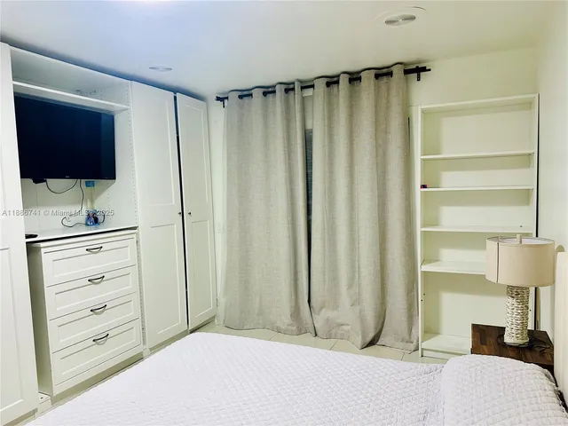 a bed sitting in a bedroom next to a window with rug