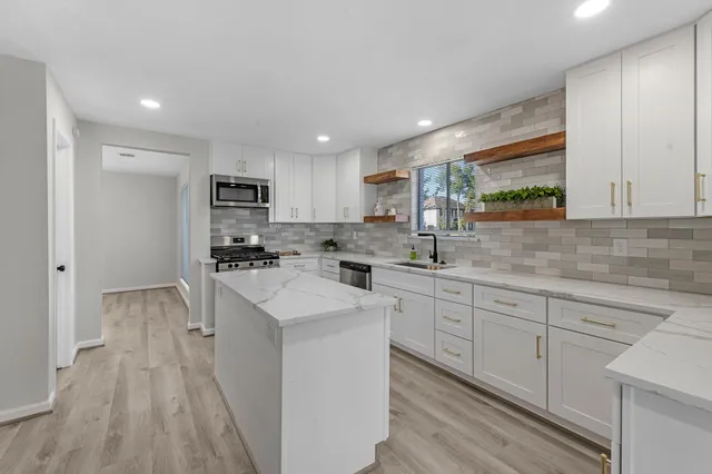 a kitchen with white cabinets appliances and a sink