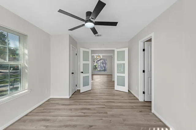 a view of an empty room with wooden floor and windows