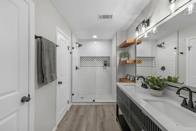 a bathroom with a double vanity sink mirror and shower
