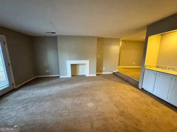 a view of an empty room with a fireplace and a window
