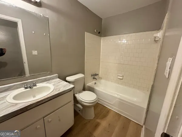 a bathroom with a sink a toilet a mirror a bathtub and shower