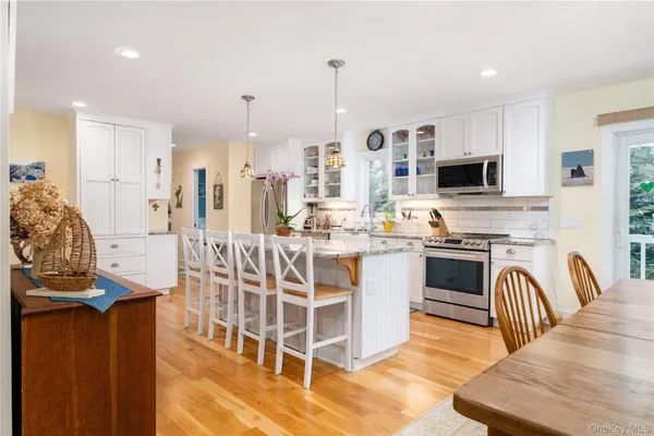 a kitchen with stainless steel appliances kitchen island granite countertop a stove a sink a oven a dining table and chairs