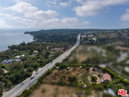 an aerial view of a residential houses with outdoor space and trees