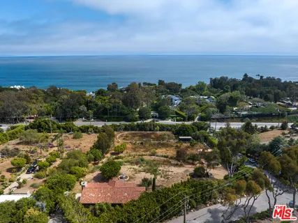 an aerial view of residential building with outdoor space and trees all around
