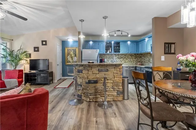 a kitchen with granite countertop a stove a sink a microwave oven a dining table and chairs with wooden floor