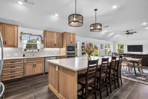 a kitchen with stainless steel appliances granite countertop wooden floor and a view of living room