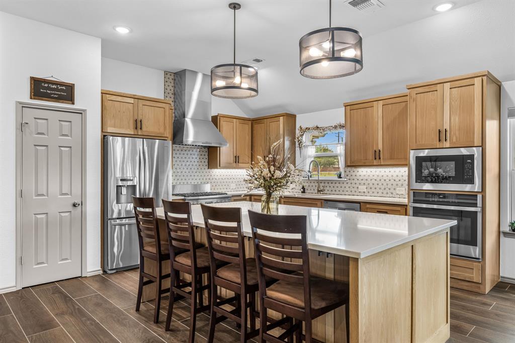9624 Wells Road Wylie, TX 75098 - Photo 3 of 25 a kitchen with stainless steel appliances granite countertop a dining table chairs refrigerator and microwave