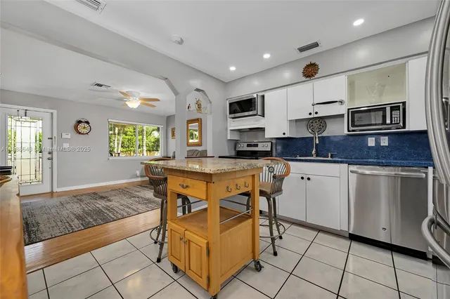 a kitchen with stainless steel appliances granite countertop a stove top oven a sink a dining table and chairs with wooden floor