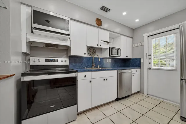 a kitchen with granite countertop white cabinets stainless steel appliances and a sink