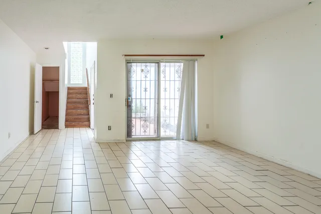 a view of an empty room with window and a kitchen