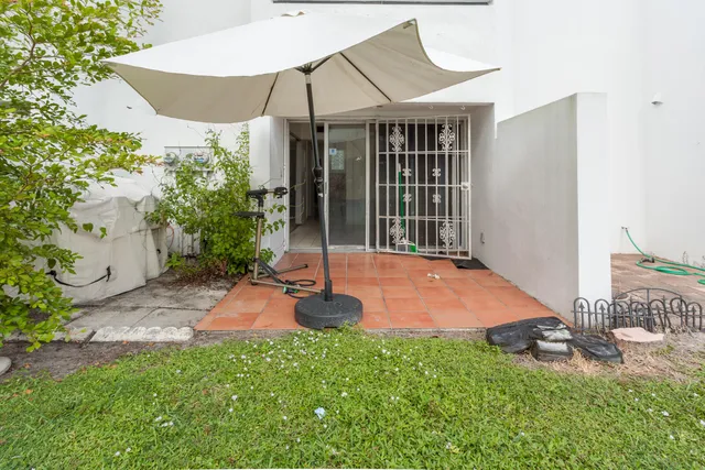 a backyard of a house with table and chairs under an umbrella