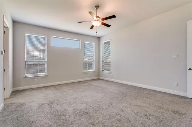 an empty room with windows and ceiling fan