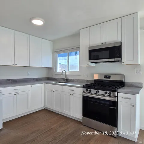 a kitchen with cabinets stainless steel appliances a sink and a wooden floor
