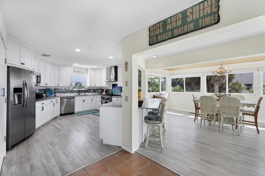 3547 Gasparilla Road Boca Grande, FL 33921 - Photo 3 of 43 a kitchen with a dining table wooden floor stainless steel appliances and cabinets