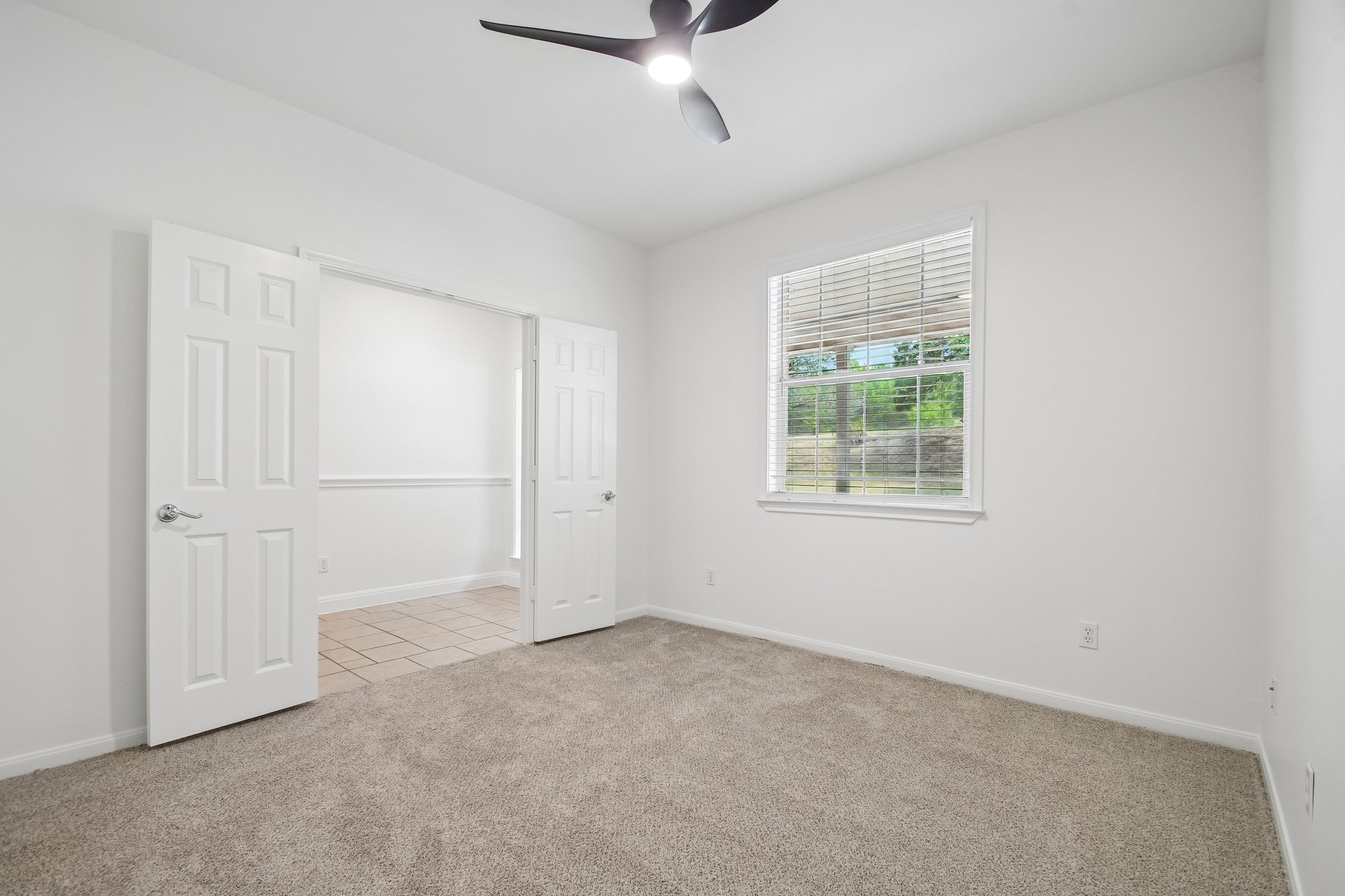 20609 Bridle Path Road Lago Vista, TX 78645 - Photo 16 of 30 A well-lit room featuring carpeted flooring, a window with blinds, and a modern ceiling fan.