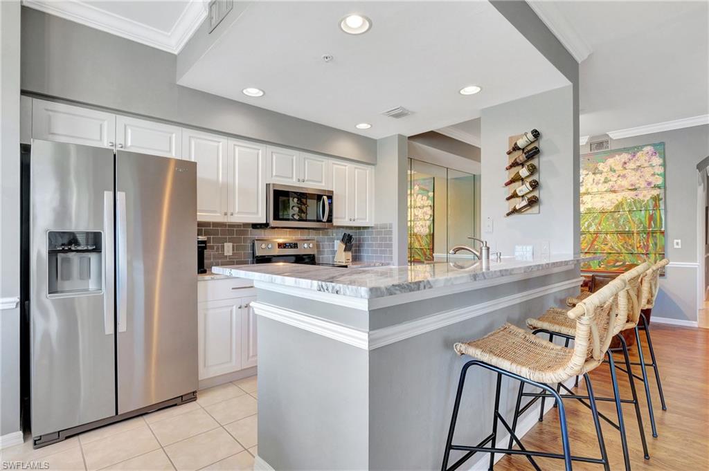 8600 Cedar Hammock Circle, Unit 1313 Naples, FL 34112 - Photo 7 of 41 a kitchen with stainless steel appliances a refrigerator a stove a sink a dining table and chairs