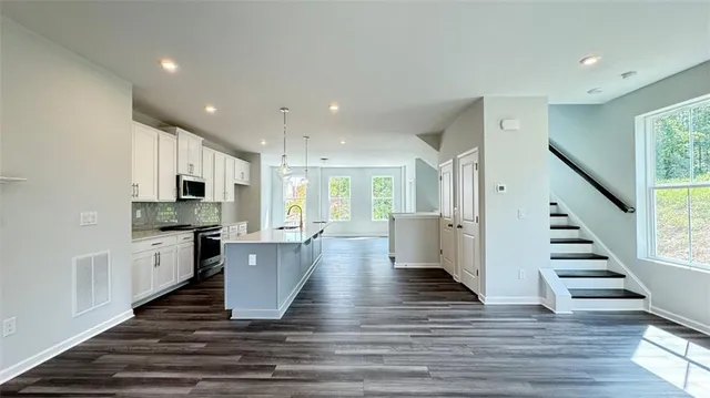 a view of a kitchen with kitchen island wooden floors stainless steel appliances and a window
