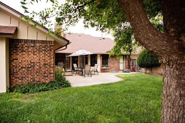 a patio with table and chairs and a big yard