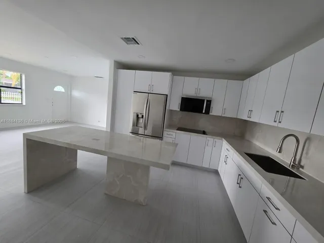 a kitchen with stainless steel appliances granite countertop a refrigerator and a stove top oven