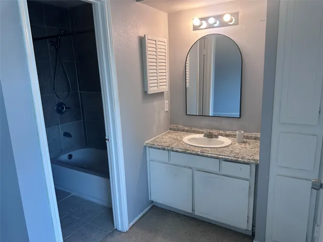 a bathroom with a granite countertop sink a mirror and a bathtub