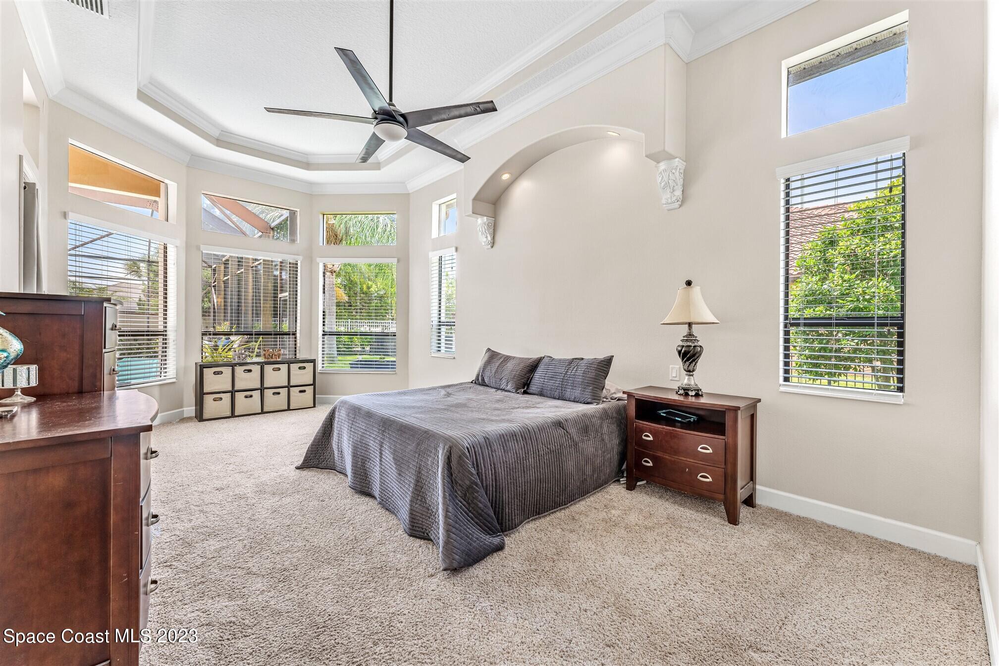 3550 Thurloe Drive Rockledge, FL 32955 - Photo 21 of 44 a spacious bedroom with a bed a chandelier and a large window