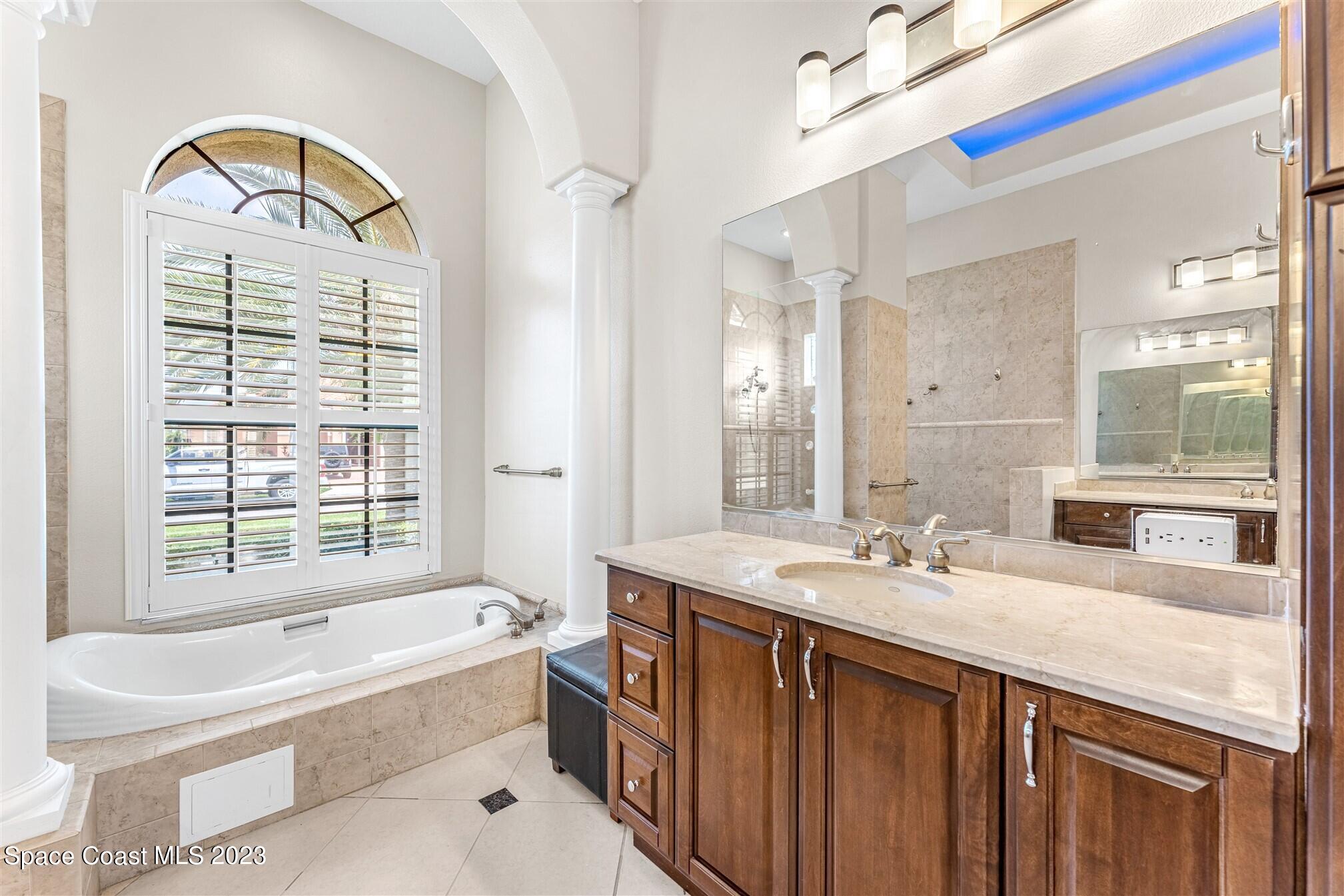 3550 Thurloe Drive Rockledge, FL 32955 - Photo 24 of 44 a bathroom with a granite countertop tub a sink and a large mirror