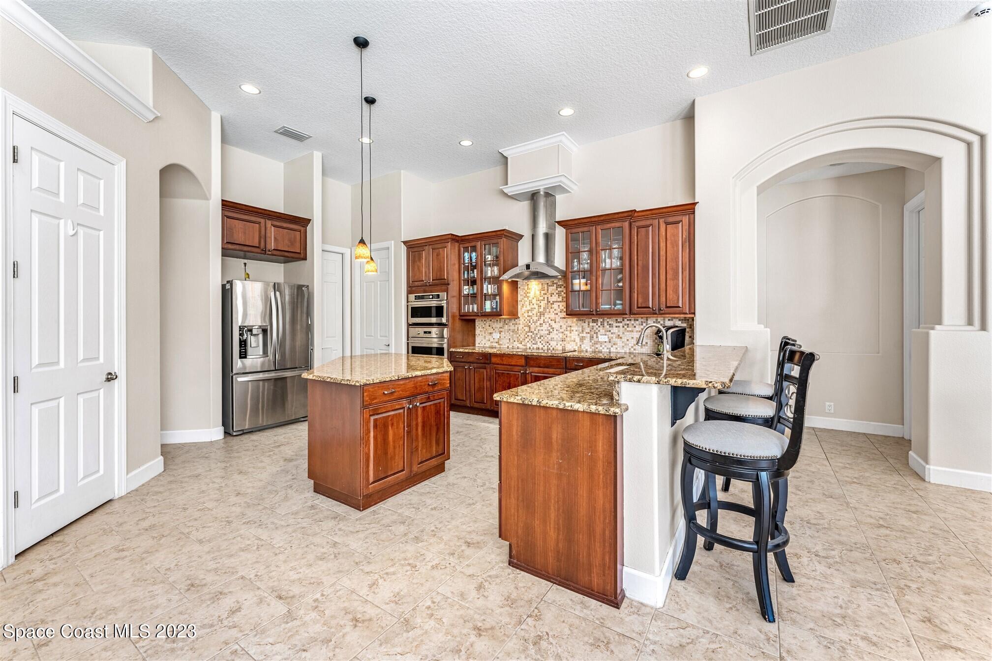 3550 Thurloe Drive Rockledge, FL 32955 - Photo 10 of 44 a kitchen with a refrigerator a stove top oven a sink dishwasher and a dining table with wooden floor
