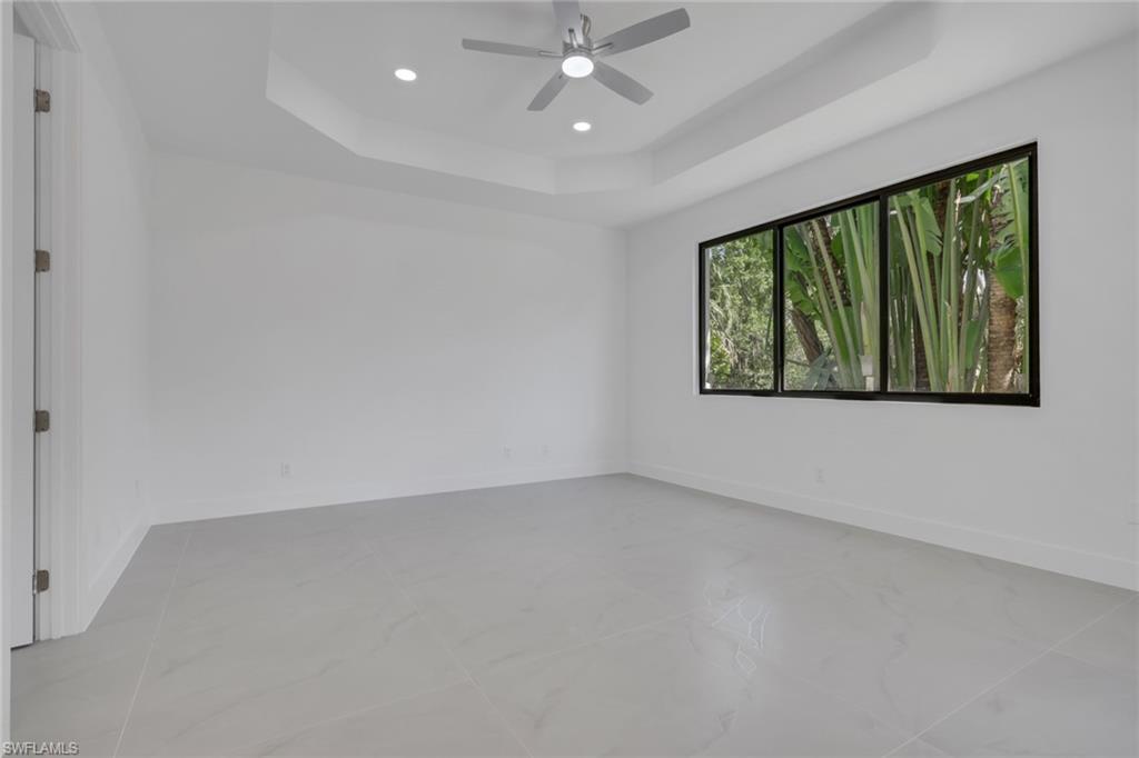 730 29th Street Southwest Naples, FL 34117 - Photo 21 of 50 Empty room featuring a tray ceiling, ceiling fan, and a chandelier