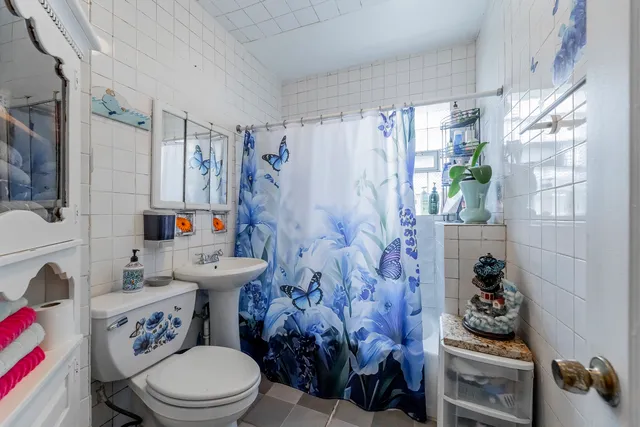 a white toilet sitting next to a bathroom sink and a shower curtain