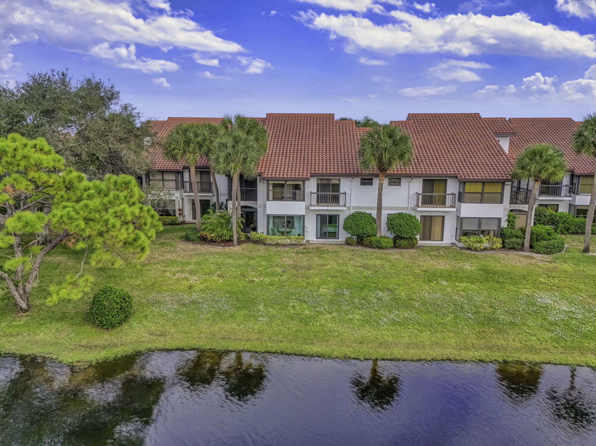 16671 Traders Crossing North, Unit 122 Jupiter, FL 33477 - Photo 32 of 34 a view of a big house with a big yard and large trees