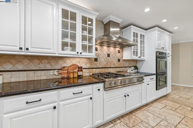 a kitchen with stainless steel appliances granite countertop a stove and a white cabinets