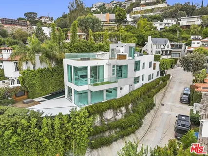 an aerial view of residential houses with outdoor space and trees all around