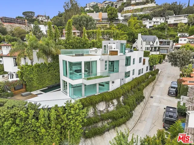 an aerial view of residential houses with outdoor space and trees all around