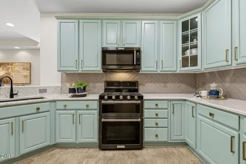 a kitchen with stainless steel appliances granite countertop a dining table chairs a refrigerator and cabinets