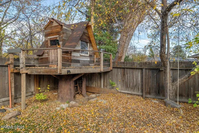 a view of a house with wooden fence next to a large tree