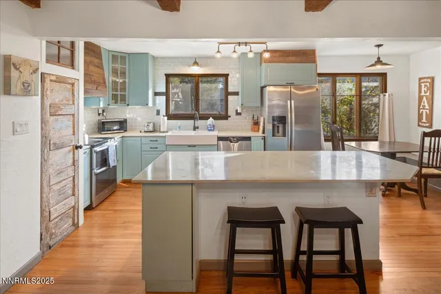 a kitchen with stainless steel appliances granite countertop table chairs and wooden floor