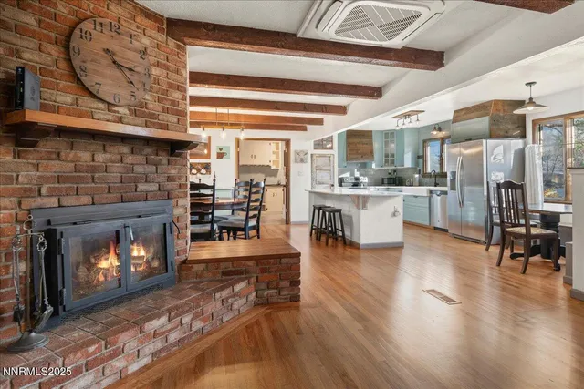 a living room with stainless steel appliances furniture a fireplace a flat screen tv and kitchen view