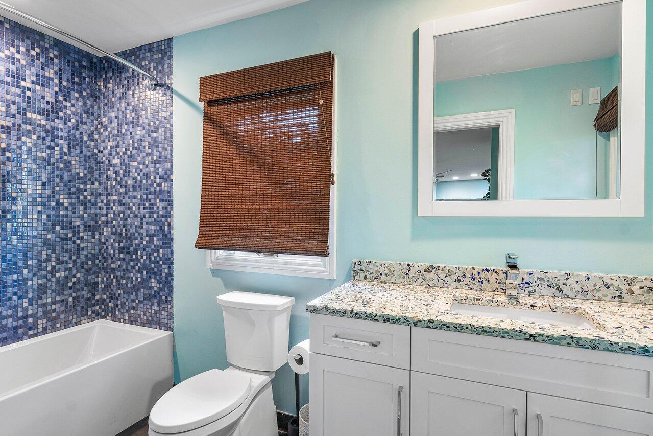 963 Eve Street Delray Beach, FL 33483 - Photo 33 of 83 a bathroom with a granite countertop toilet a sink and a bathtub
