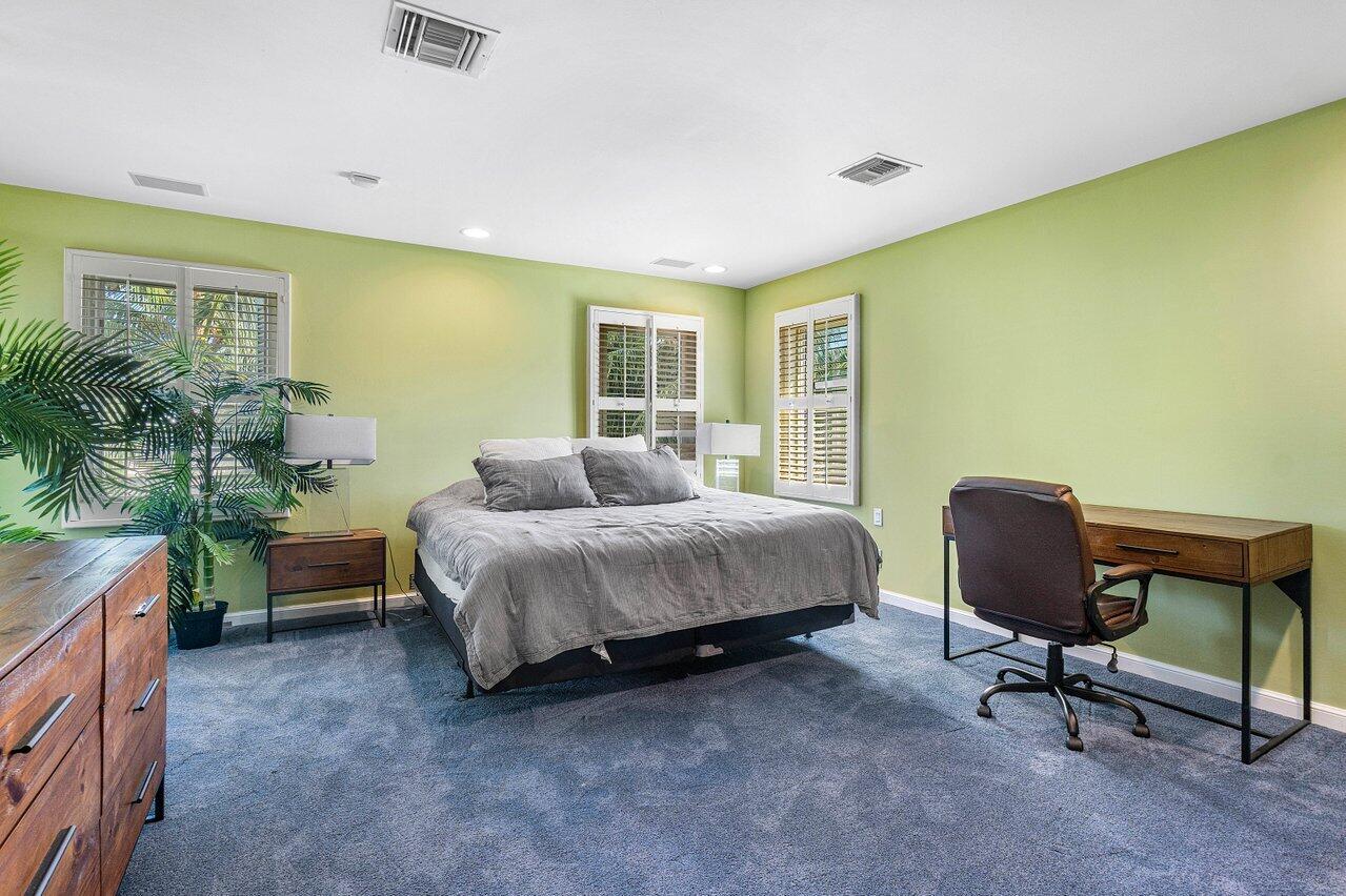 963 Eve Street Delray Beach, FL 33483 - Photo 50 of 83 a spacious bedroom with a bed and a chair