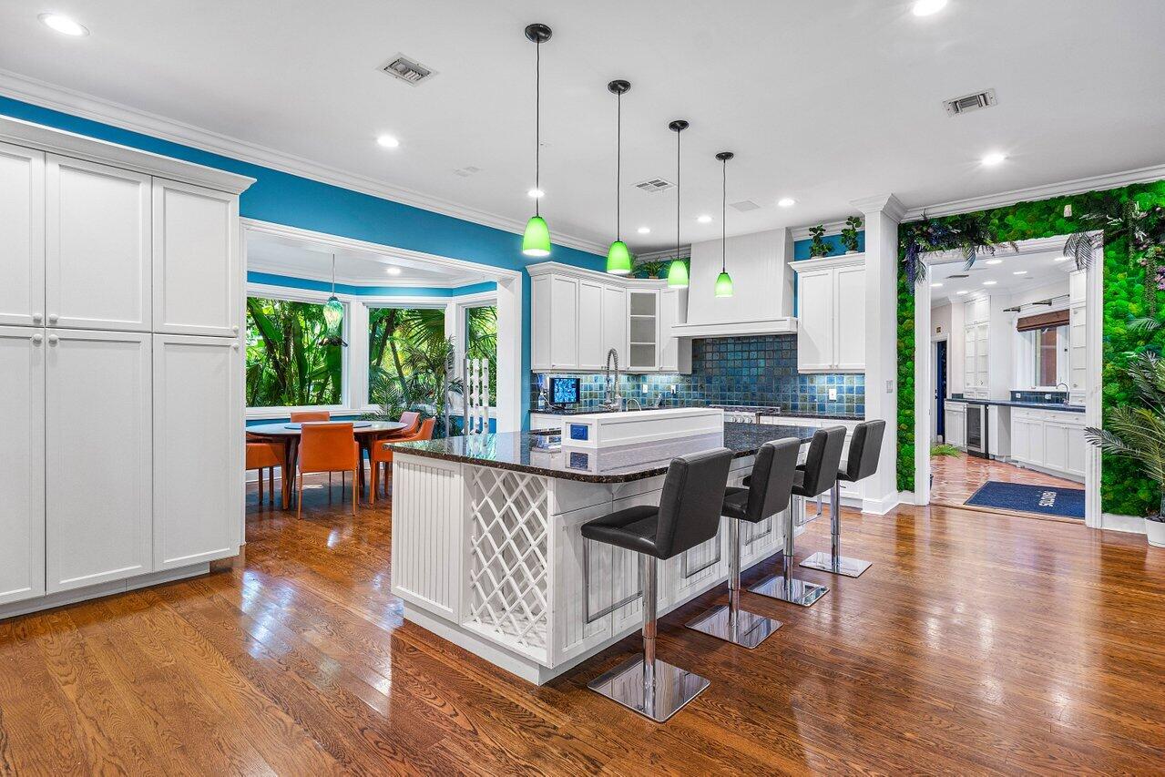 963 Eve Street Delray Beach, FL 33483 - Photo 7 of 83 a kitchen with stainless steel appliances granite countertop a stove a refrigerator a kitchen island a dining table and chairs with wooden floor