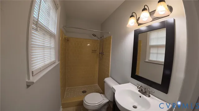 a bathroom with a sink a toilet a mirror and shower