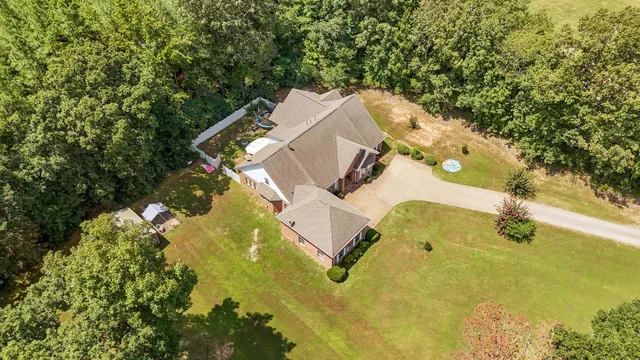 an aerial view of a house with swimming pool and large trees
