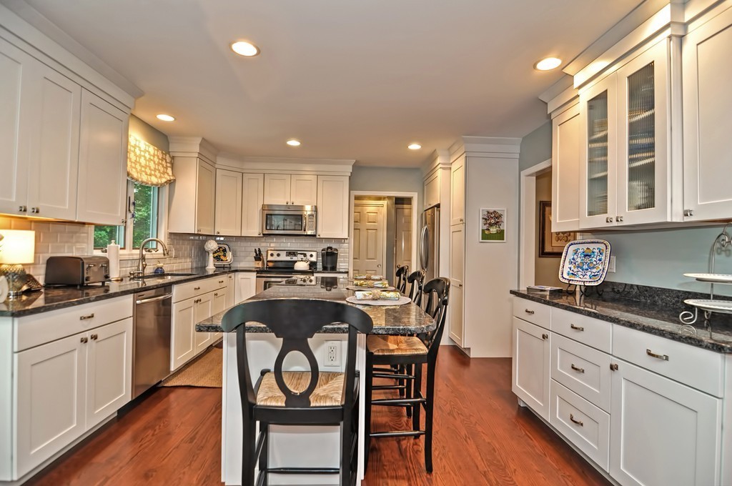 4 Nottingham Way Stoneham, MA 02180 - Photo 13 of 30 a kitchen with stainless steel appliances granite countertop a stove top oven a sink dishwasher a dining table and chairs with wooden floor