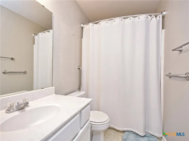 a bathroom with a sink a toilet and shower curtain