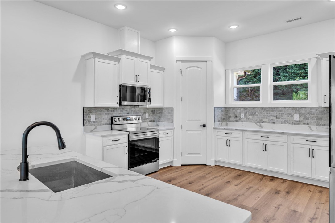 1727 Harris Bridge Road Anderson, SC 29621 - Photo 8 of 35 Modern kitchen featuring crisp white cabinetry, marble countertops, and warm wood flooring.