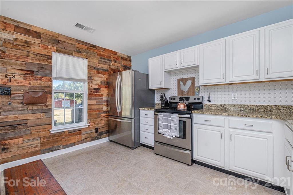 6107 Stack Road Monroe, NC 28112 - Photo 6 of 24 a kitchen with stainless steel appliances granite countertop a stove and white cabinets