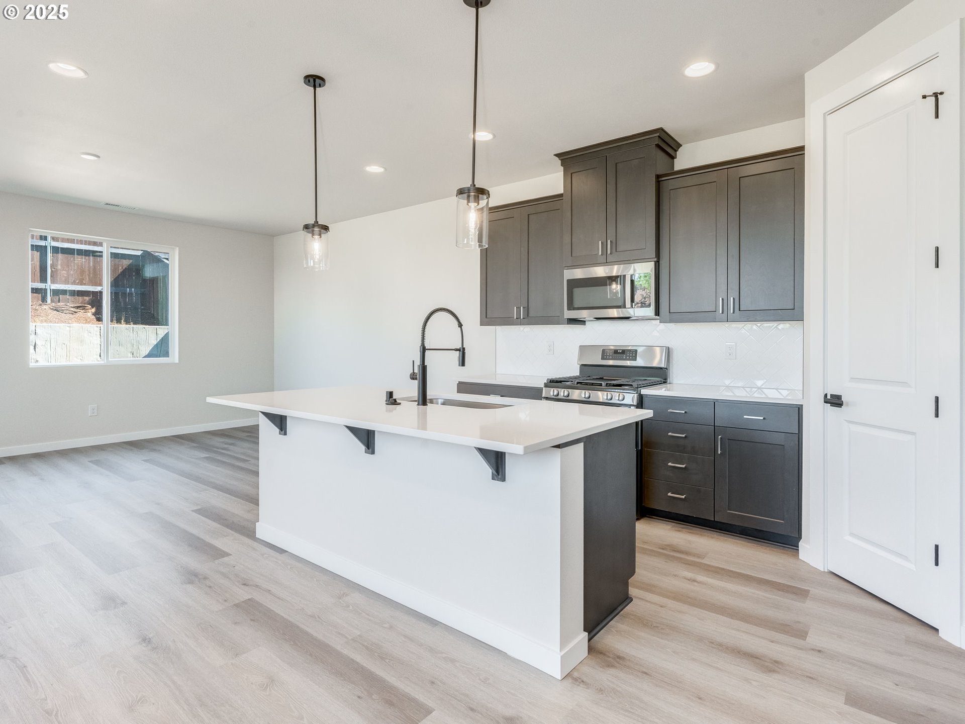 744 Northwest 178th Street Ridgefield, WA 98642 - Photo 2 of 25 a kitchen with stainless steel appliances granite countertop a sink a stove a refrigerator and island with wooden floor