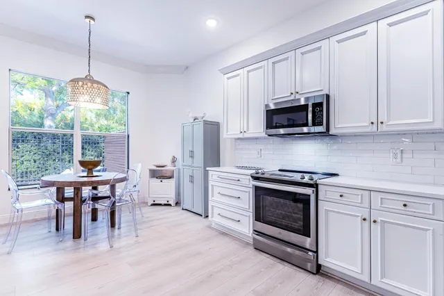 a kitchen with stainless steel appliances granite countertop a stove a sink a microwave a refrigerator and white cabinets